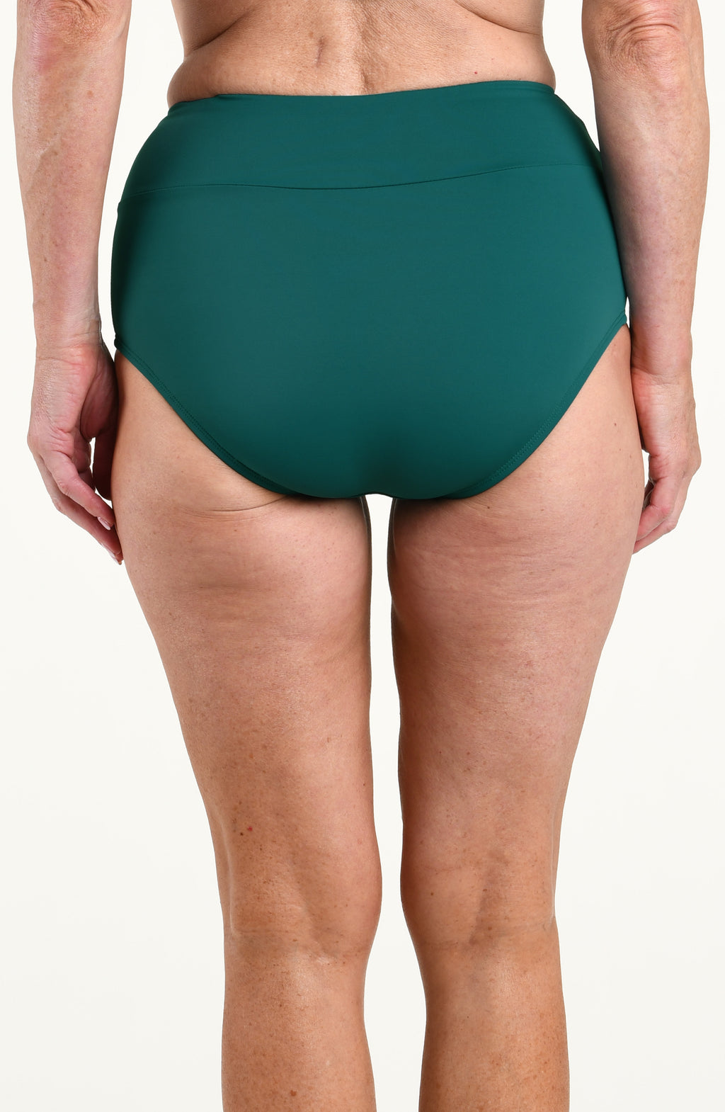 Woman wearing solid dark green bikini bottoms against a white background. 