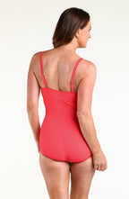 Woman wearing a bright orange bandeau one piece swimsuit against a white background. 