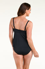 Woman wearing a solid black tankini top and matching swim skirt against a white background 