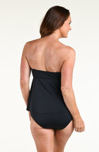 Woman wearing a solid black tankini top and matching swim skirt against a white background 