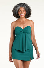 Woman wearing a jungle green tankini top and matching swim skirt against a white background 