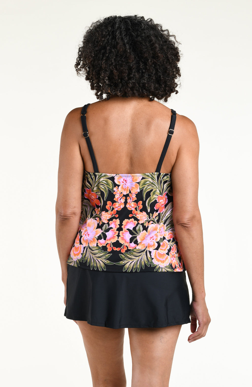 Woman wearing a black multicolored tankini top and solid black swim skirt against a white background. 