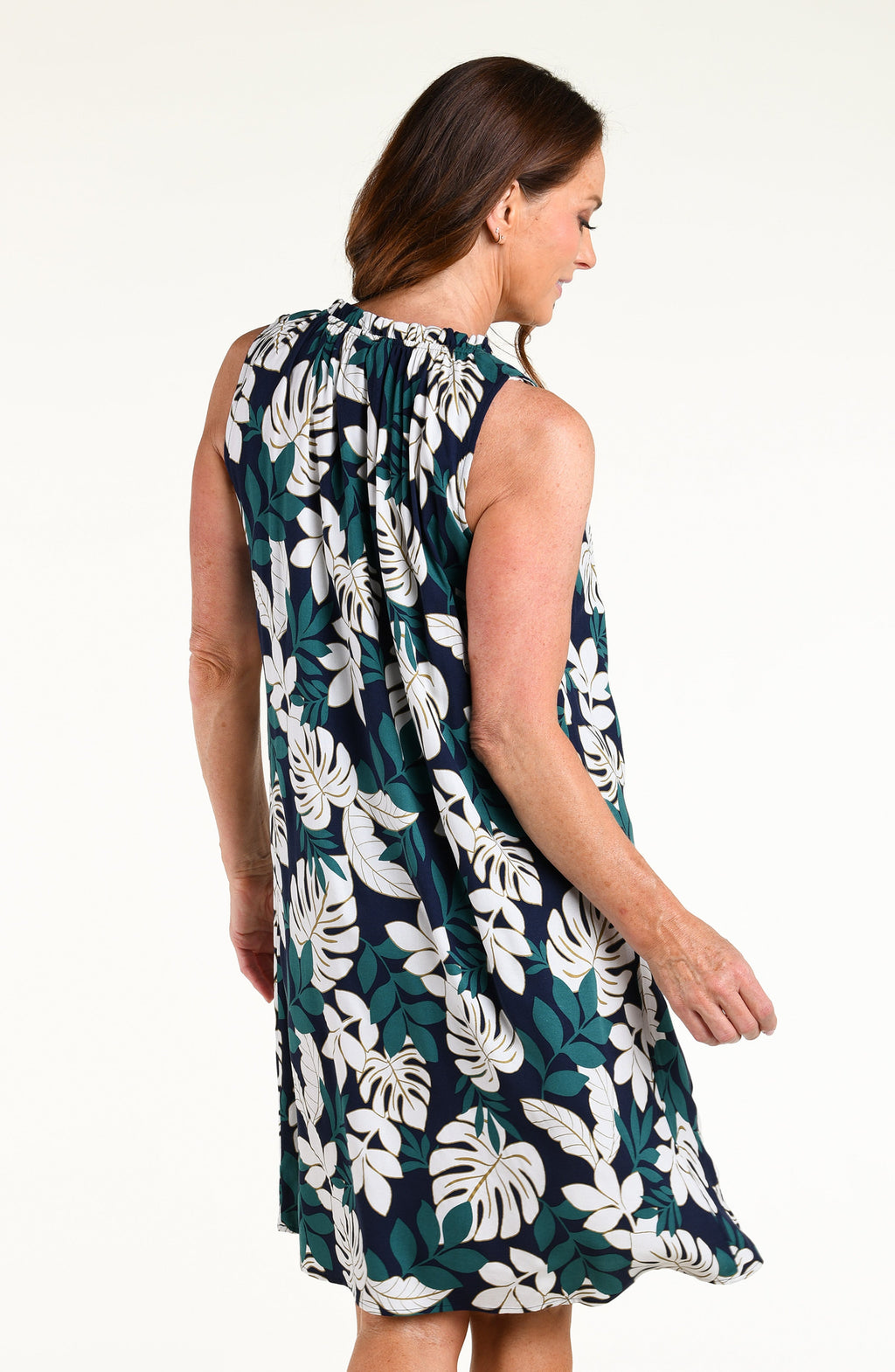Woman wearing a green multicolored mini dress cover up against a white background.