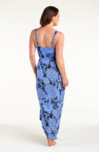 Woman wearing an indigo blue multicolored one piece swimsuit and matching sarong against a white background. 