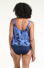Woman wearing an indigo blue multicolored tankini top and solid indigo blue bikini bottoms against a white background. 