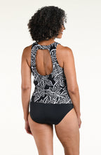 Woman wearing a black and white multicolored tankini top with a solid black bottom against a white background. 