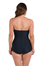 Model is wearing a solid black Bandeau Girl Leg One Piece.