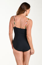 Woman wearing a floral one piece swimsuit against a green background.