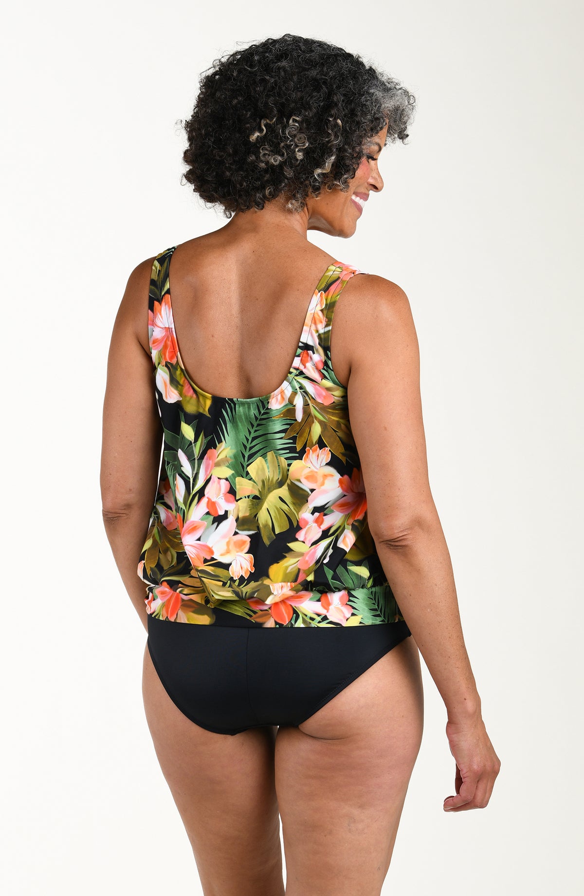 Woman wearing a floral tankini top and black bottoms on a white background