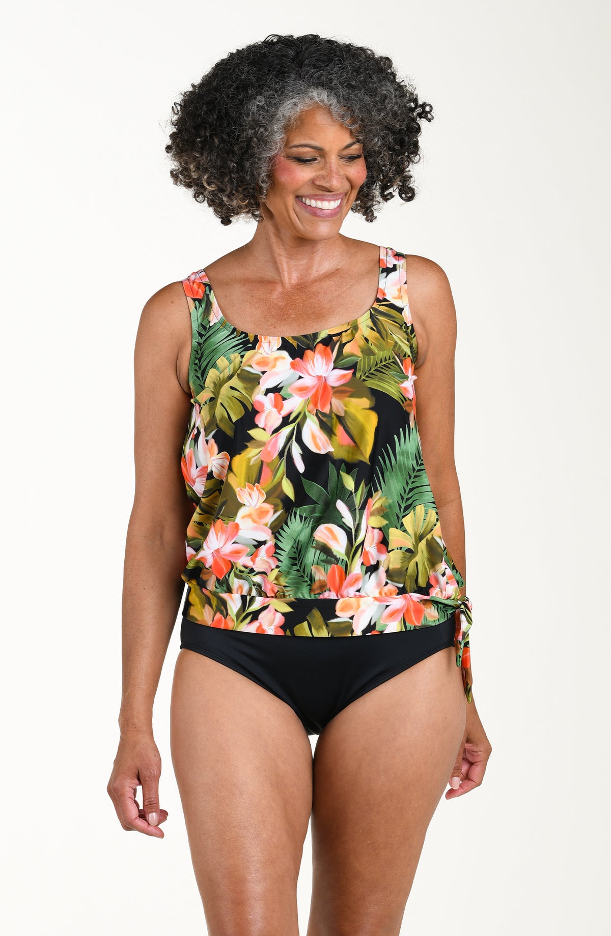 Woman wearing a floral tankini top and black bottoms on a white background