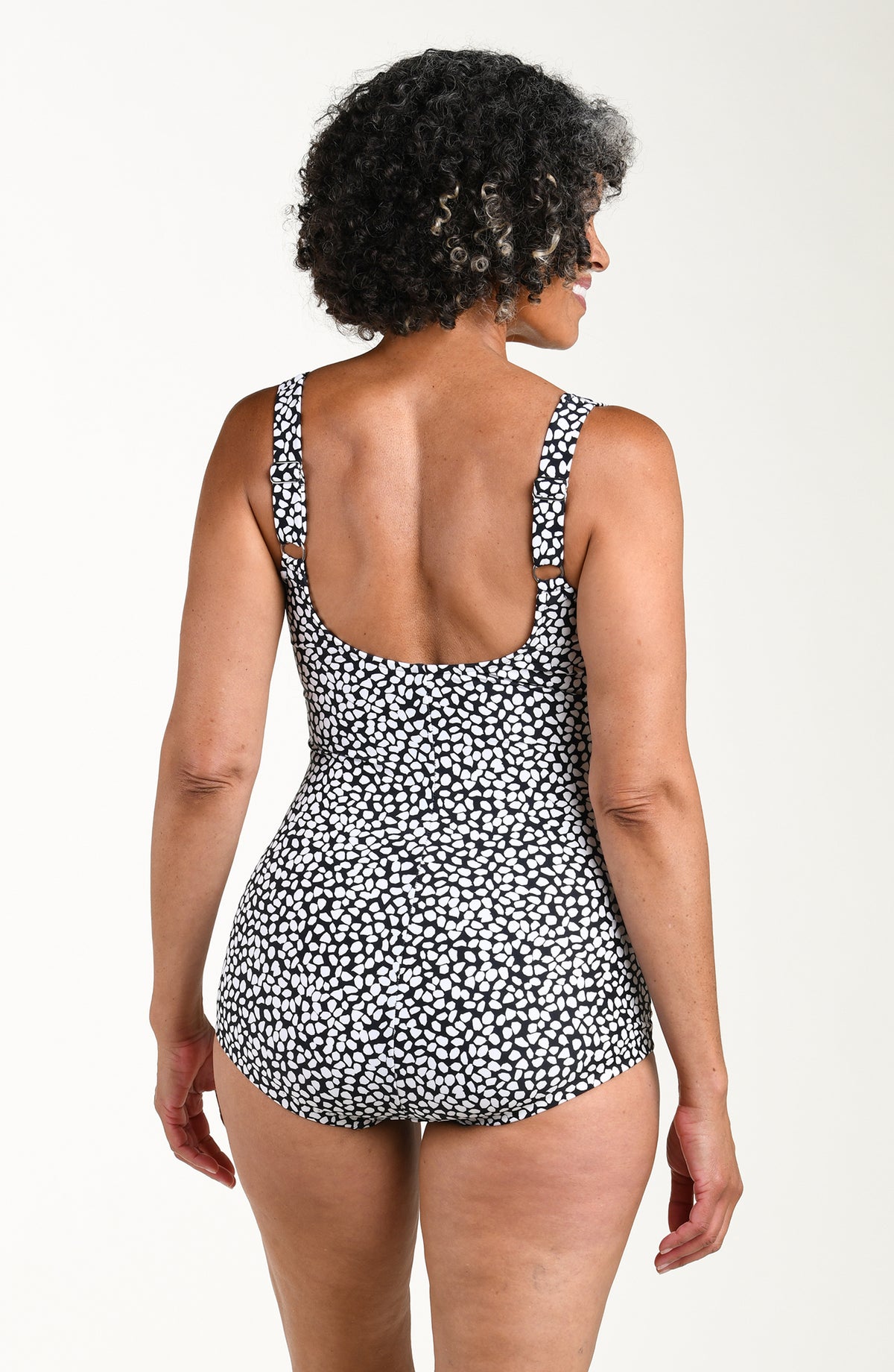Woman wearing a black and white patterned one piece swimsuit on a white background