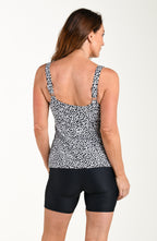 Woman wearing a black and white patterned tankini top and black shorts on a white background