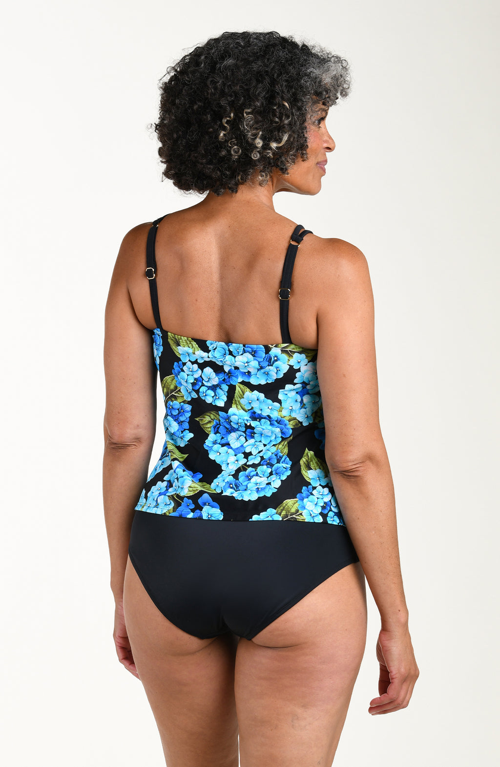 Woman wearing a floral tankini top and black bottoms on a white background