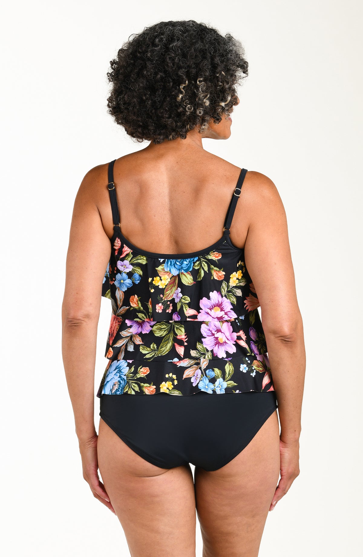 Woman wearing a floral tankini top and black bottoms on a white background