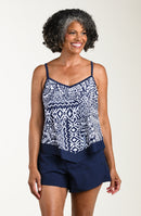 Front image of model wearing a multicolored navy blue paisley printed tankini top featuring thin adjustable straps, a V-neckline, and a flowy handkerchief hem. This is paired with matching colored board shorts.