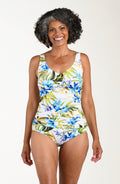 Front image of model wearing a multicolored (white) tropical one-piece with wide adjustable straps, V-neckline, twist front and front ruching. 