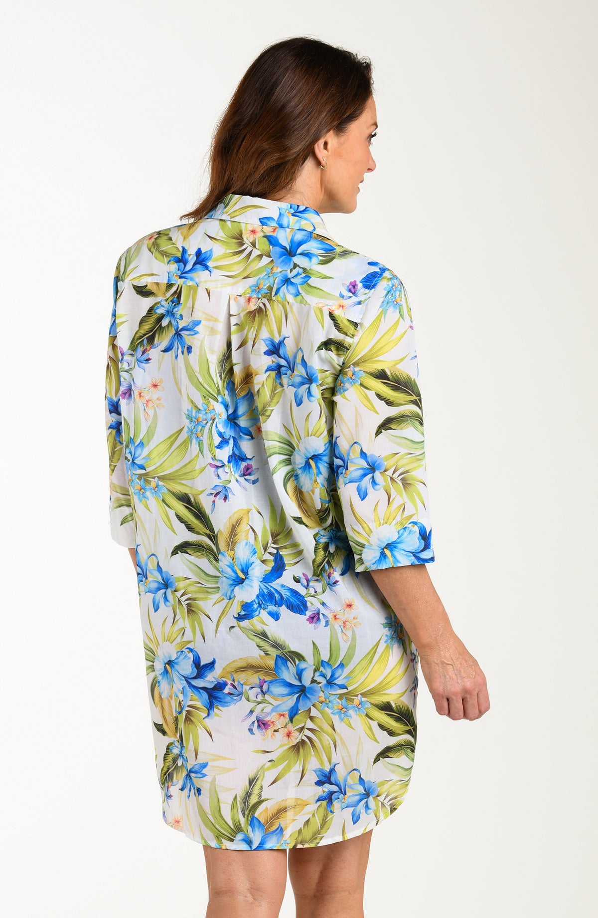 Back image of model wearing a multicolored (white) tropical tunic cover up featuring a collared button front and three quarter sleeves. 