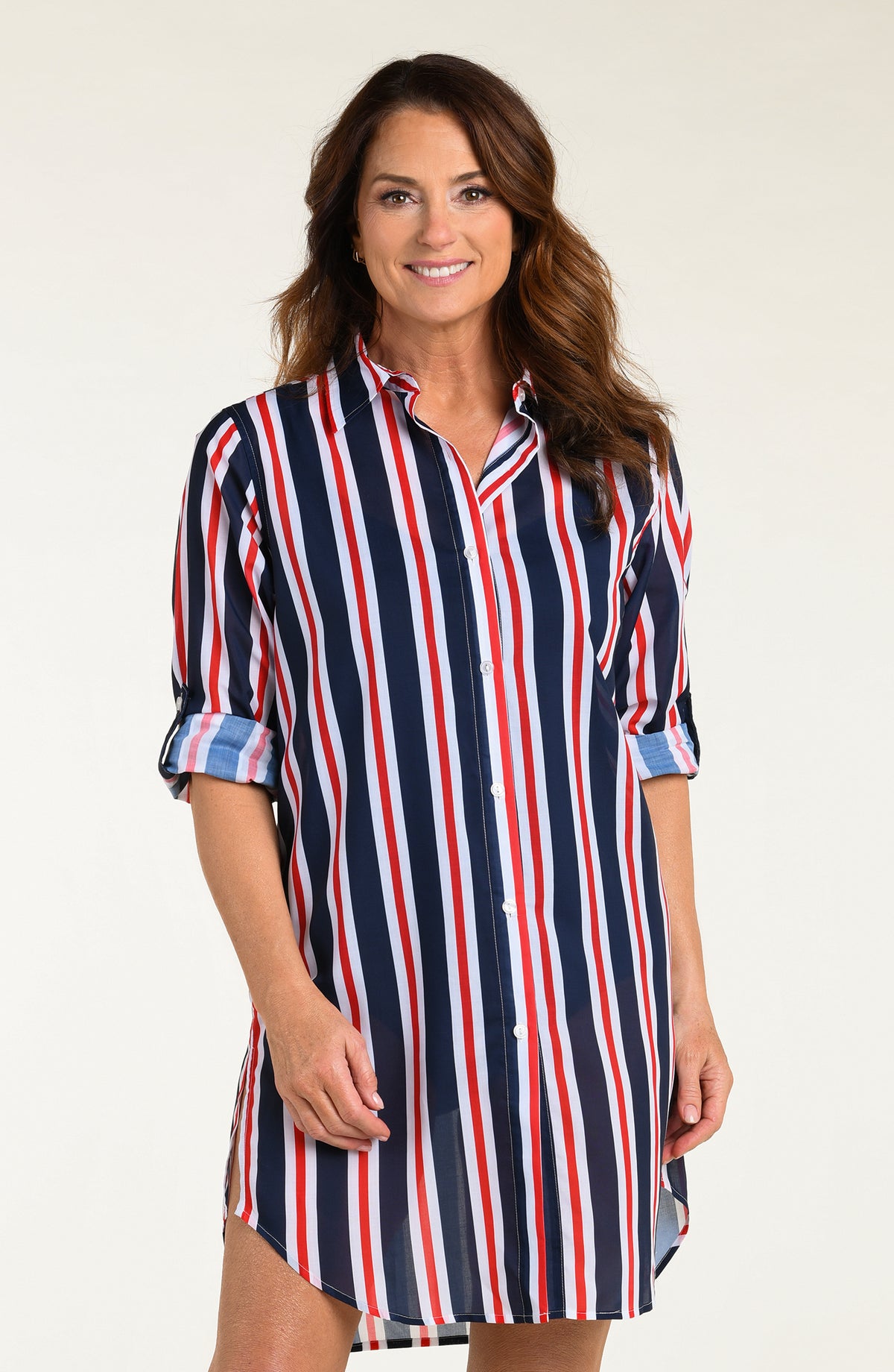 Woman wearing a red, white, and blue striped button down tunic against a white background.