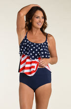 Woman wearing a tankini top with American flag design and navy bottoms against a plain background
