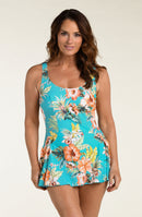 Woman wearing a turquoise floral swim dress against a white background