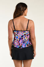 Woman wearing a colorful floral tankini top and black swim skirt on a white background