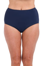 A close-up of a model wearing high-waisted navy blue bikini bottoms against a plain white background.