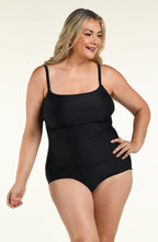 Woman wearing a solid black one piece swimsuit against a white background. 