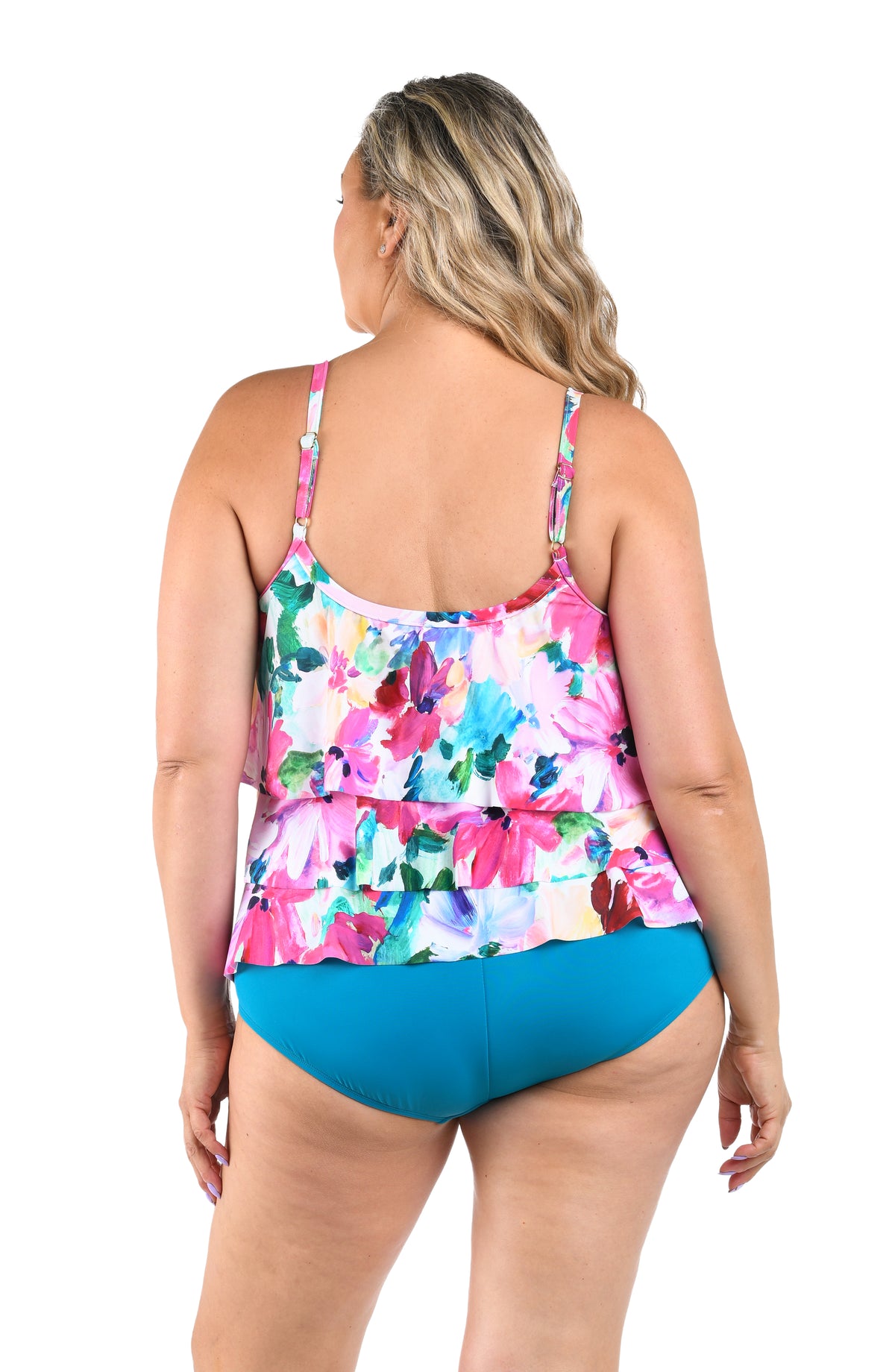 Woman wearing a colorful floral tankini top with emerald bottoms against a white background.