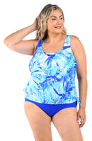 Woman wearing a blue and white patterned tankini top and high-waisted blue bottoms on a white background