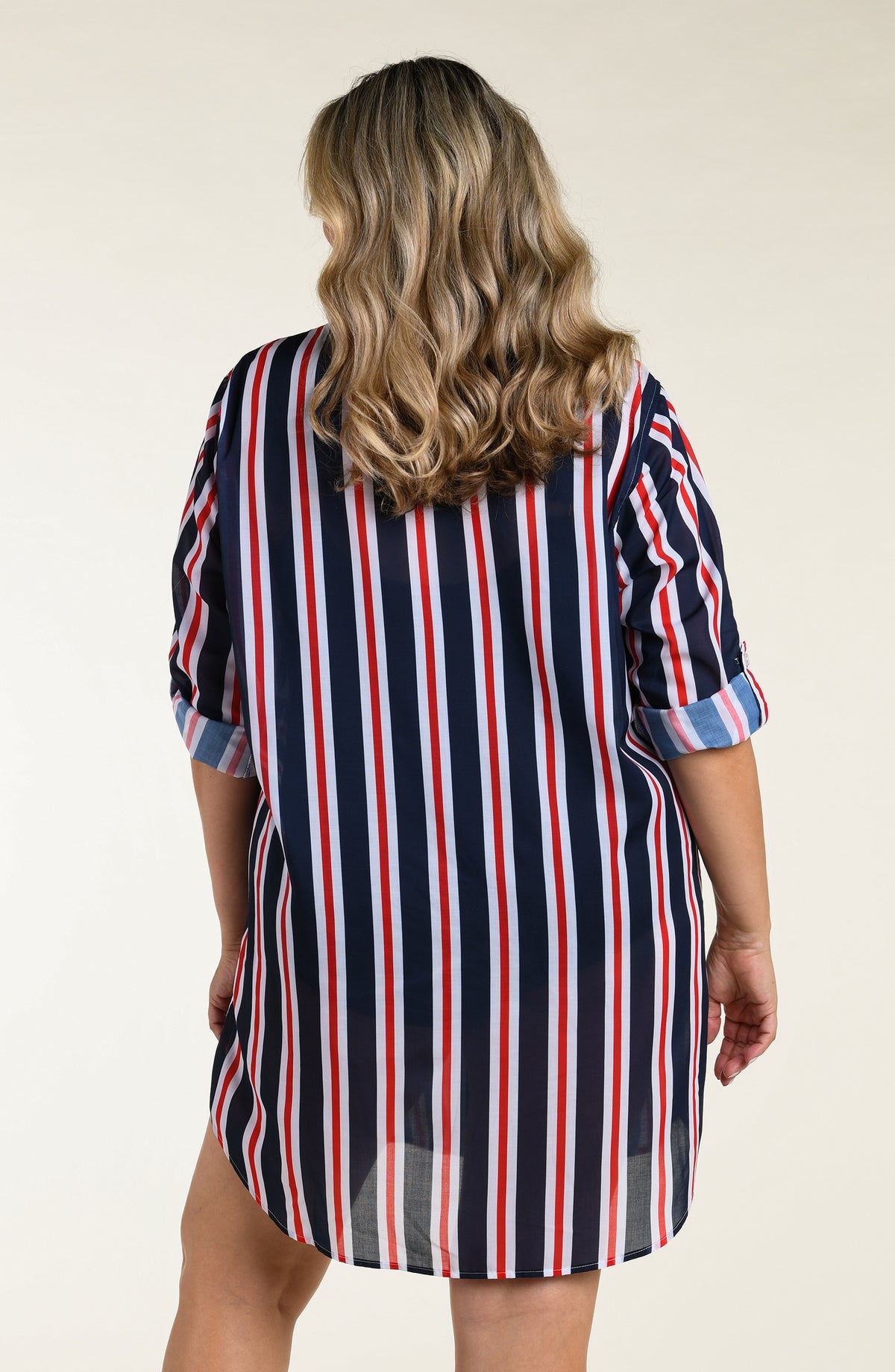 Woman wearing a navy, red, and white striped button down tunic against a plain background