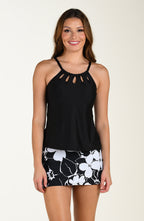 Front image of model wearing a multicolored black and white floral printed swim skort featuring a high waist, built in short, and pocket. This is paired with a solid black tankini top.