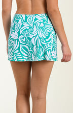 Teal and white tropical patterned swim skirt worn by a person on a beige background