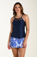Woman wearing a navy top and blue and white patterned skirt on a beige background