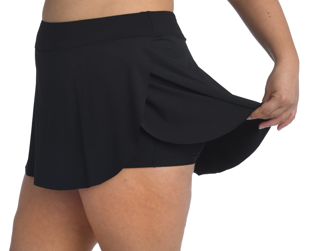 Model is wearing a solid navy blue colored petal skort swim bottom from our 24th & Ocean brand.