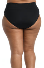 Model is wearing a solid black mid waist spliced hipster bikini bottom from our 24th & Ocean brand.