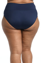 Model is wearing a solid midnight blue mid waist spliced hipster bikini bottom from our 24th & Ocean brand.